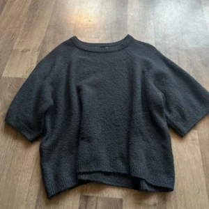 Marin blå stickad tröja med kort ärm - Marin blå stickad tröja med rund hals och korta ärmar. Modellen är loose fit och har ribbade detaljer vid hals och nederkant. Perfekt för dig som gillar enkel och stilren look med lite oversized känsla.