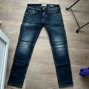 Replay jeans mörkblå, 30/30 - Snygga mörkblå Replay jeans med klassisk femficksdesign och gul patch bak. Modellen är anbass. Jeansen har en slim passform och är tillverkade i jeansmaterial med snygga slitningar och sömmar. Perfekta för dig som gillar stilrena och moderna jeans. Storlek 30/30 och är i toppskick.