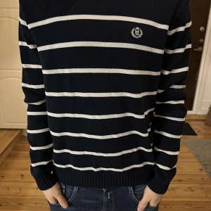 Randig tröja från Henri Lloyd vintage - Snygg marinblå tröja från Henri Lloyd med vita ränder och broderad logga på bröstet. Knappt använd, säljs ej längre. 