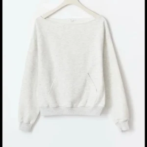 Ljusgrå sweatshirt med ficka - En enkel och stilren ljusgrå sweatshirt med rund hals och en praktisk magficka. Tröjan har långa ärmar med ribbade muddar och en loose passform som gör den skön att bära. Perfekt för chill dagar eller när du vill ha något bekvämt.