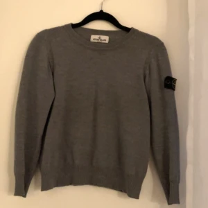 Grå stickad tröja Stone Island Junior - Stone Island stickad tröja 10 år. Bra skick förutom att den har två små hål på baksidan av tröjan. 
