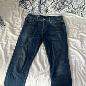 Replay Hyperflex jeans blå, stl 31 - Säljer ett par Replay Hyperflex jeans i klassisk blå tvätt med snygga slitningar och kontrastsömmar. Modellen heter MICKYM och har fem fickor samt Replay-logga på fickan. Sköna stretchjeans som sitter riktigt bra och passar till allt.