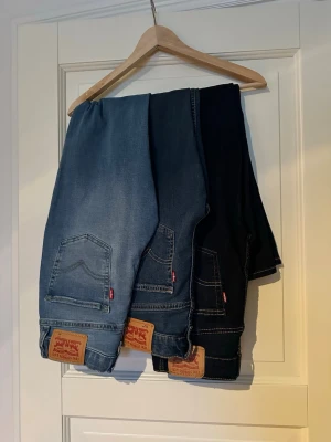 Levi's 512 jeans i olika blå nyanser - Säljer flera par Levi's 512 jeans i olika blå och mörkblå nyanser. Klassisk femficksmodell med raka ben och snygga kontrastsömmar. Tillverkade i slitstark bomullsdenim med den ikoniska Levi's-lappen bak. Perfekta för dig som gillar tidlös och clean stil. Alla är i samma storlek och för ett bra pris