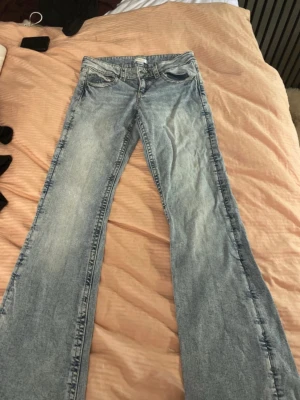 Ljusblå bootcut jeans - Säljer ett par ljusblå bootcut jeans med klassisk femficksdesign och dragkedjegylf. Jeansen har en utsvängd passform nedtill och är tillverkade i mjukt denimtyg. Perfekta för dig som gillar retrovibbar och vill ha ett par riktigt snygga jeans. OBBBSSS!! DOM HAR EN LITEN FLÄCK UNDER FICKAN! syns ej när man har på dom!