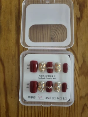 Vinröda press-on naglar med glitter - Snygga press-on naglar i vinrött med accentnaglar dekorerade med silverglitter och pärlor. Mix av matta och glansiga ytor, vissa naglar har 3D-effekt med stenar. Perfekt för dig som vill ha en trendig och glam look. Kommer i praktisk förpackning.