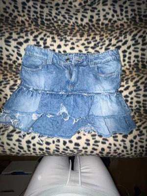 Volangig jeanskjol - Säljer en blå jeanskjol med volanger och fransiga kanter. Den är från Gina tricot och är storlek 152