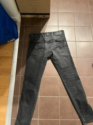 Replay anbass svarta L30 W28 - Snygga svart/grå jeans med raka ben och diskret tvätt. Klassisk femficksmodell med silverfärgade detaljer och normal passform. Perfekta till en avslappnad stil och funkar året runt.