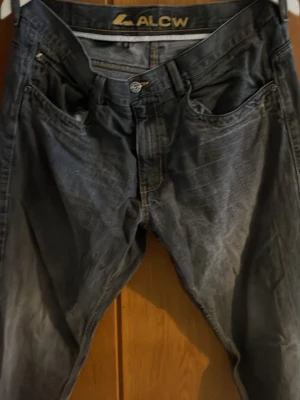 Svarta jeans från ALCW med raka ben - Säljer ett par svarta jeans från ALCW med klassisk femficksmodell och raka ben. Jeansen har en något tvättad look och är tillverkade i slitstarkt denimtyg. Perfekta för dig som gillar en enkel och stilren stil.