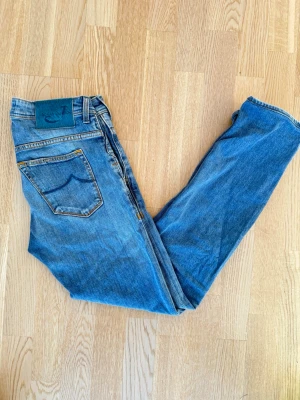 Blå Jeans från Jacob Cohen - Säljer ett par klassiska blå jeans från Replay med en unik turkos patch bak i midjan och kontrastsömmar. Jeansen har rak passform och fem fickor, tillverkade i slitstark bomullsdenim. Perfekta för dig som gillar en tidlös och avslappnad look. Size 30! Frågor kom pm, allt gott/ Neo!💫