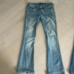 True Religion Joey Low Rise Flare Jeans - Säljer ett par ljusblå True Religion Joey jeans med låg midja och utsvängda ben. Den är i storlek 23 men den är uppsydda och passar mig som är 155❤️