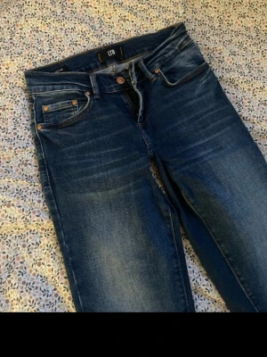 Blå bootcut jeans från LTB - Snygga blå jeans från LTB med klassisk femficksmodell och bootcut-ben. Jeansen har en mörk tvätt med lätt slitning och kontrastsömmar. Perfekta för dig som gillar en tidlös och avslappnad stil. Omsydda till low waist. Storlek Xs. Litet hål som nog kan gå sy igen(vet dock ej) säljer då ja köpte dem men de passade ej💗pris kan ändras, kom med prisförslag!!