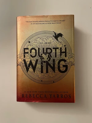 Fourth Wing av Rebecca Yarros  - Snygg fantasybok med skimrande guld och röd omslag, stora svarta bokstäver och drakmotiv. Boken är skriven av Rebecca Yarros och handlar om drakar, äventyr och farliga prövningar. 