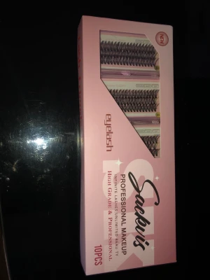 Sackvis lösögonfransar 10-pack - Säljer ett set med 10 par professionella lösögonfransar från Sackvis. Fransarna kommer i en rosa förpackning och är svarta med volym och längd för en intensiv look. Perfekta för att skapa en dramatisk ögonmakeup. Materialet är syntetiskt och designen är flerdelad.