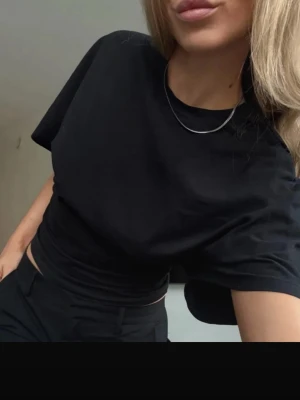 Svart basic t-shirt i bomull - En stilren svart t-shirt i mjuk bomull med klassisk passform och rund halsringning. Perfekt att matcha med jeans eller kjol för en enkel och snygg look.