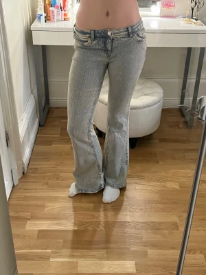 Ljusblå bootcut jeans - Säljer ett par ljusblå bootcut jeans med klassisk femficksdesign och låg midja. Jeansen har en snygg tvättad look.40 cm rakt över midjan och  76 cm i innerbenslängd