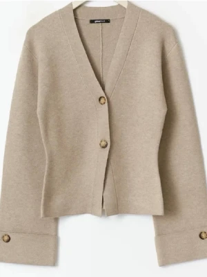 Beige v-ringad kofta Gina Tricot - Beige kofta från Gina Tricot med v-ringning och två stora knappar framtill. Koftan har vida ärmar med dekorativa knappar vid ärmsluten och är gjord i ett mjukt, stickat material. Enkel och clean design som är lätt att styla. Den är använd en gång och säljer den på grund av att den inte passade. 