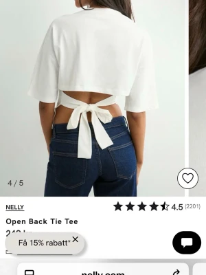 Vit t-shirt med öppen rygg och knyt - Trendig vit t-shirt från Nelly med öppen rygg och breda knytband bak. Modellen har korta ärmar och en croppad passform som ger en cool och modern look. Perfekt till jeans eller kjol för en avslappnad stil.