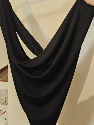 Svarta top med korsning i ryggen - Säljer en svart top som är draperad och korsas i ryggen. Glansigt material. Jättefin till sommaren. 