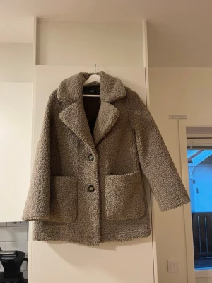 Beige teddyjacka - Mysig beige teddyjacka från Zara med stora framfickor och bred krage. Jackan har två knappar framtill och är tillverkad i fluffigt teddy-material 🧸❣️