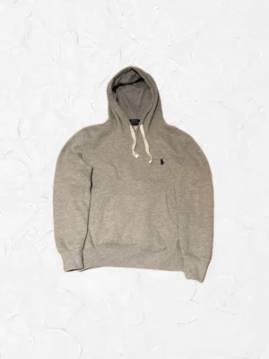 Grå hoodie från Polo Ralph Lauren - Snygg grå hoodie från Polo Ralph Lauren med klassisk huva och vita dragsnören. Den är storlek S men sitter lite mindre