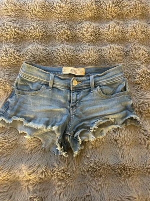 Hollister shorts - Säljer ett par blå jeansshorts från Hollister med fransig kant och slitningar. Dem är i storlek 24❤️