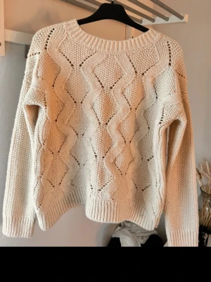 Beige stickad tröja från H&M - Säljer en beige stickad tröja från H&M med grovt kabelstickat mönster och rund halsringning. Tröjan har långa ärmar och ribbade muddar vid ärmslut och nederkant. Perfekt för lager på lager under kyliga dagar.