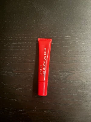 Lumene Lip Glow Oil Balm röd - Lumene Lip Glow Oil Balm i en snygg röd tub på 10 ml. Läppbalsamet har en oljebaserad formula som ger glans och återfuktar läpparna. Förpackningen är smidig och lätt att ta med i väskan. Perfekt för dig som vill ha mjuka och glansiga läppar med en hint av färg.