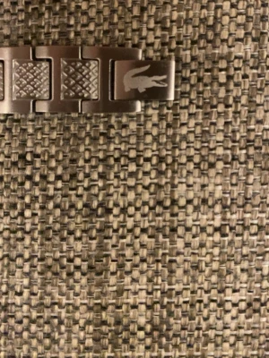 Silverfärgat armband från Lacoste - Stilrent armband i silverfärgad metall från Lacoste med länkdesign och ingraverad krokodil på en av länkarna. Några länkar har ett diskret rutmönster som ger extra detalj. Perfekt accessoar för en modern look.