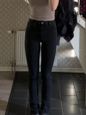 Svarta jeans  - Säljer ett par svarta jeans med hög midja. Jeansen har smal passform och är tillverkade i stretchigt denimtyg.