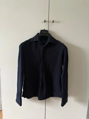 Mörkblå Eton skjorta - Mörkblå Eton skjorta i storleken S slim fit. Skjortan är i mycket bra skick, och stryker självklart den innan frakt! Säljes då den är för liten.