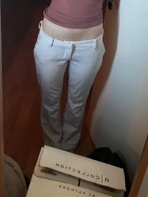 Vita kostymbyxor med raka ben - Snygga vita kostymbyxor med raka ben och klassisk passform. Byxorna har hällor för bälte, diskreta fickor bak och stängs med dragkedja och knapp framtill. Perfekta för en clean och stilren look.