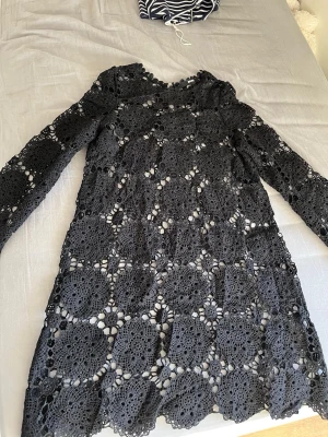 Svart spetsklänning från BikBok - Säljer en svart kort spetsklänning från BikBok i storlek XS. Klänningen har lång ärm och är täckt av ett detaljerat spetsmönster med blommiga inslag. Perfekt för dig som gillar en unik och elegant look.