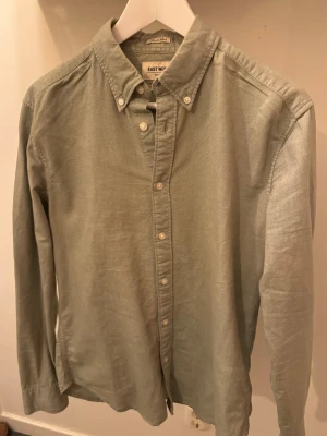 Grön skjorta från East West - Snygg grön skjorta från East West i slim fit-modell. Skjortan har klassisk krage med knappar, långa ärmar och är tillverkad i mjuk bomull. Perfekt för dig som gillar enkel och stilren design.