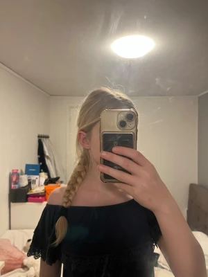 Mörkblå offshoulder topp med spets - Snygg mörkblå offshoulder topp med dekorativa spetsdetaljer längs bröstet och ärmsluten. Toppen är croppad och har en feminin, somrig look. Perfekt att styla med jeans eller kjol.