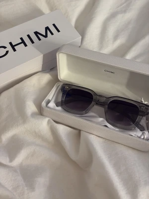 Grå transparenta solglasögon CHIMI - Snygga solglasögon från CHIMI med transparent grå båge och mörka glas. Rektangulär form som ger en modern vibe. Kommer med originalfodral och box. Perfekt accessoar för att lyfta din stil. använda två gånger, hör av er vid frågor!🥰