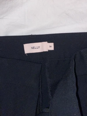 Svarta bootcut jeans från Nelly - Säljer ett par svarta kostymbyxor från Nelly i storlek 36. Jeansen har en klassisk femficksmodell och sitter snyggt med en lätt utsvängd passform nedtill. Perfekta till en trendig och avslappnad look.