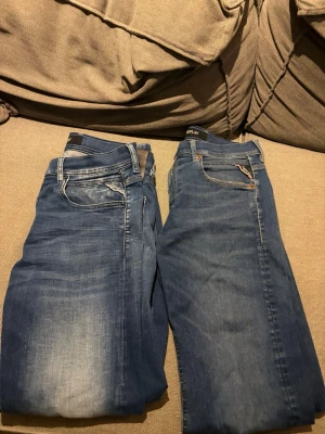 Blå Replay jeans, rak passform - Säljer ett par klassiska blå jeans från Replay med rak passform och snygga slitningar framtill. Jeansen har fem fickor, normal midja och är tillverkade i mjuk bomullsdenim. Perfekta för en avslappnad och stilren look. 