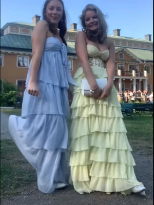 Gul långklänning med volanger - Säljer en ljusgul långklänning med volanger och spetsdetaljer upptill. Klänningen har hjärtformad byst och flera lager i kjolen för en flowy look. Perfekt för bal! 💛 har endast haft på mig den en gång och den är i nyskick ❤️