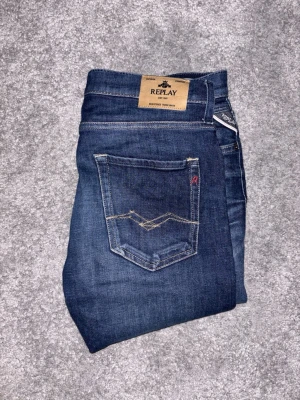 Blå jeans från Replay - Snygga blå jeans från Replay med klassisk femficksdesign och kontrastsömmar. Använda 2-3 gånger men skicket är 10/10. Modell Thad och Storlek 16A H166 cm