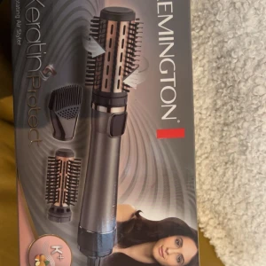 Remington Keratin Protect varmluftsborste - Remington Keratin Protect varmluftsborste i metallicgrå och roséguld med två utbytbara borsthuvuden och en stylingmunstycke. Perfekt för att skapa volym och mjuka lockar. Borsten har keramisk beläggning med keratin och mandelolja.