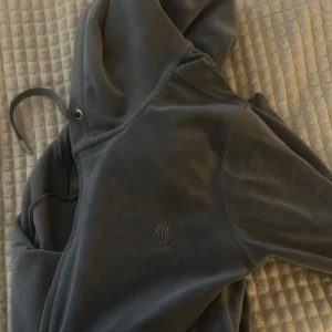 Mörkgrå hoodie från Juicy Couture - Jag säljer nu en mörkgrå hoodie från Juicy Couture då jag inte har hunnit köpa mjukisbyxorna till så den har bara legat och inte kommit till användning! Koftan har huva med snörning och är tillverkad i mjuk polyesterblandning. Perfekt för en mysig hemma dag eller något skönt att ta på sig! 