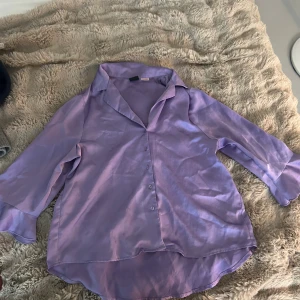 Lila satinblus från Gina Tricot - Skjortan i S och byxorna i xs. Säljer en lila satinblus från Gina Tricot i storlek S. Blusen har en snygg glansig finish, knappar framtill, klassisk krage och långa ärmar med volangdetalj vid ärmslut. Perfekt för dig som vill sticka ut med en färgglad och trendig look. Finns några fläckar på den men syns knappt när den är på. 🥰🥰