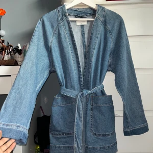 Jeansjacka med knytband - Snygg blå jeansjacka med knytband. Jackan har en fin struktur och är i fint skick, knappt använd. Storlek M passar även S. Går att bära med och utan knytband