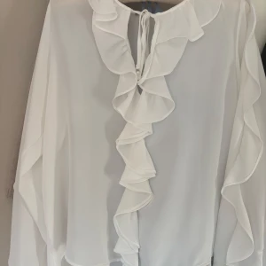 Zara vit volangblus strl S - Romantisk vit blus från Zara i lätt material med volangdetaljer. Perfekt både till kontoret och fest. Mycket fint skick. 