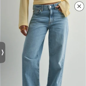 Blåa wide jeans med slitningar - Snygga ljusblå jeans med bred passform och slitna detaljer på benen. Klassisk femficksmodell med knapp och dragkedja framtill. Jeansen har en relaxed vibe och är perfekta för en trendig streetstyle-look. Storlek 38 men passar 36