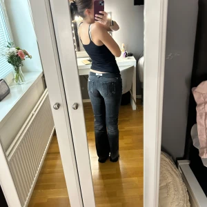 Mörkgrå bootcut jeans med slitningar - Säljer ett par mörkgrå jeans med bootcut passform och låg midja. Jeansen har slitna detaljer framtill och bakfickor med dekorativa sömmar. Det är gamla fornarina jeanssom inte går att köpa längre. Står inte någon storlek i men passar mig som har 25/xs-s men skulle nog säga dom är 26