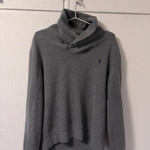 Grå tröja Polo Ralph Lauren  - Mysig grå tröja från Polo Ralph Lauren i 100% bomull. Tröjan har lång ärm, hög krage med knappar och en liten broderad logga på bröstet. Perfekt för lager-på-lager och chill dagar. Pris diskuteras!