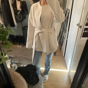 Beige kappa från H&M med bälte - En beige kappa från hm som är i storlek M. Kappan är helt ny. Den är lite för stor för mig och kommer inte ha nån användning för den💕