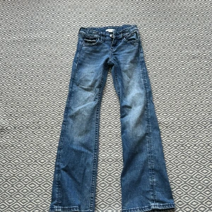 Blå bootcut jeans med rosett från Gina Tricot - Snygga blå bootcut jeans från Gina Tricot i storlek 146. Jeansen har klassisk femficksdesign, dekorativa rosetter med paljettdetaljer på bakfickorna och normal passform. Tillverkade i mjukt denimtyg med lätt tvättad look. Ny pris 400kr❤️