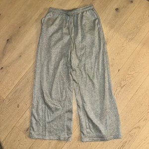 Grå mjukisbyxor  - Gråa mjukisbyxor med breda ben och elastisk midja med snörning. Byxorna har en loose passform och är tillverkade i mjukt bomullsmaterial. Perfekta för en chill och avslappnad stil.